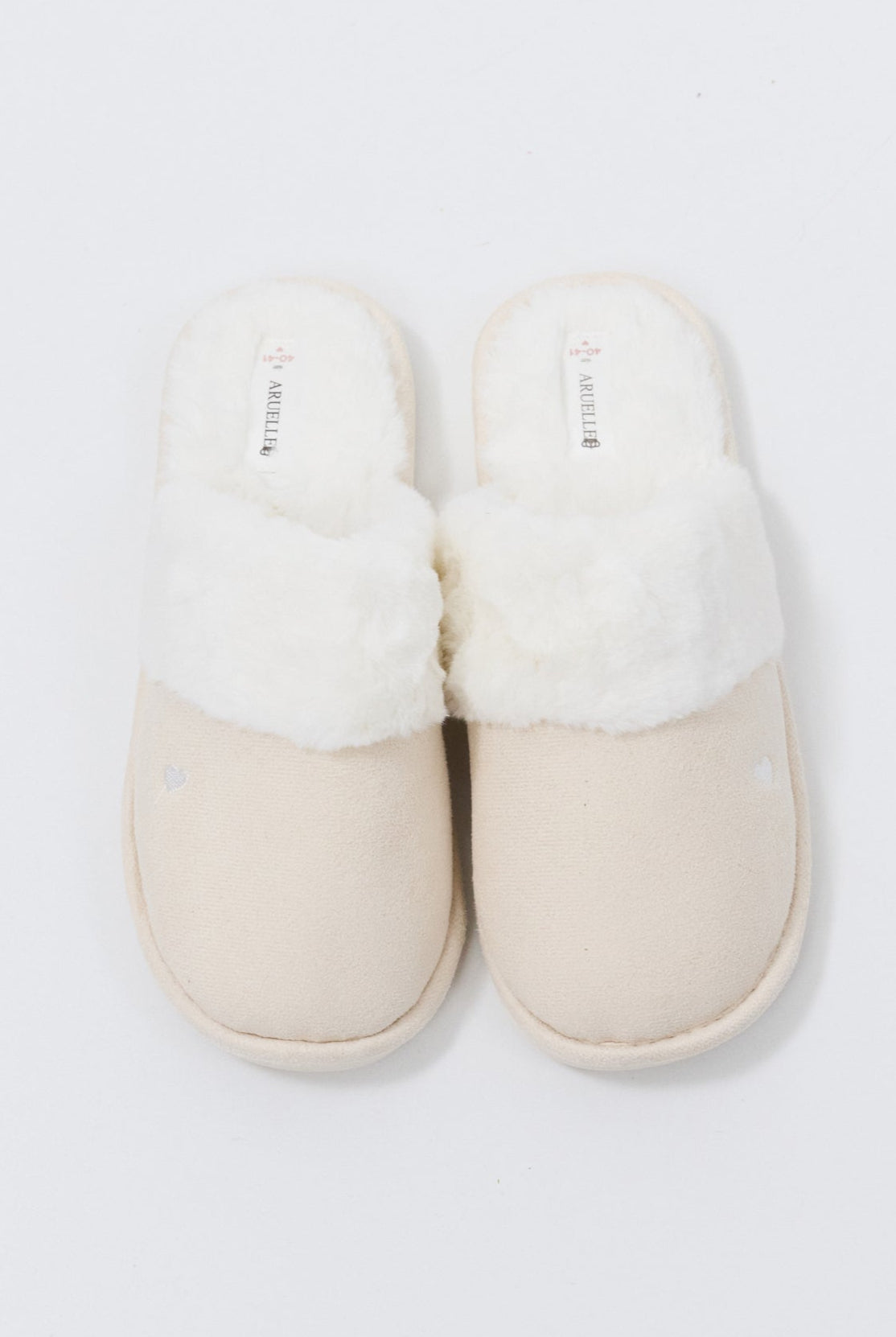 Pair of white slippers with fluffy white interior on a light gray background