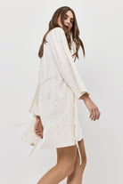 Woman wearing a white gown with long sleeves on a plain background