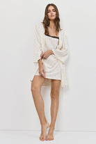 Woman wearing a white nightdress and gown on a plain background