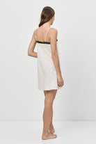 Woman wearing a white nightdress with black straps on a white background