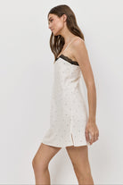 Woman wearing a white nightdress with black lace trim on a white background