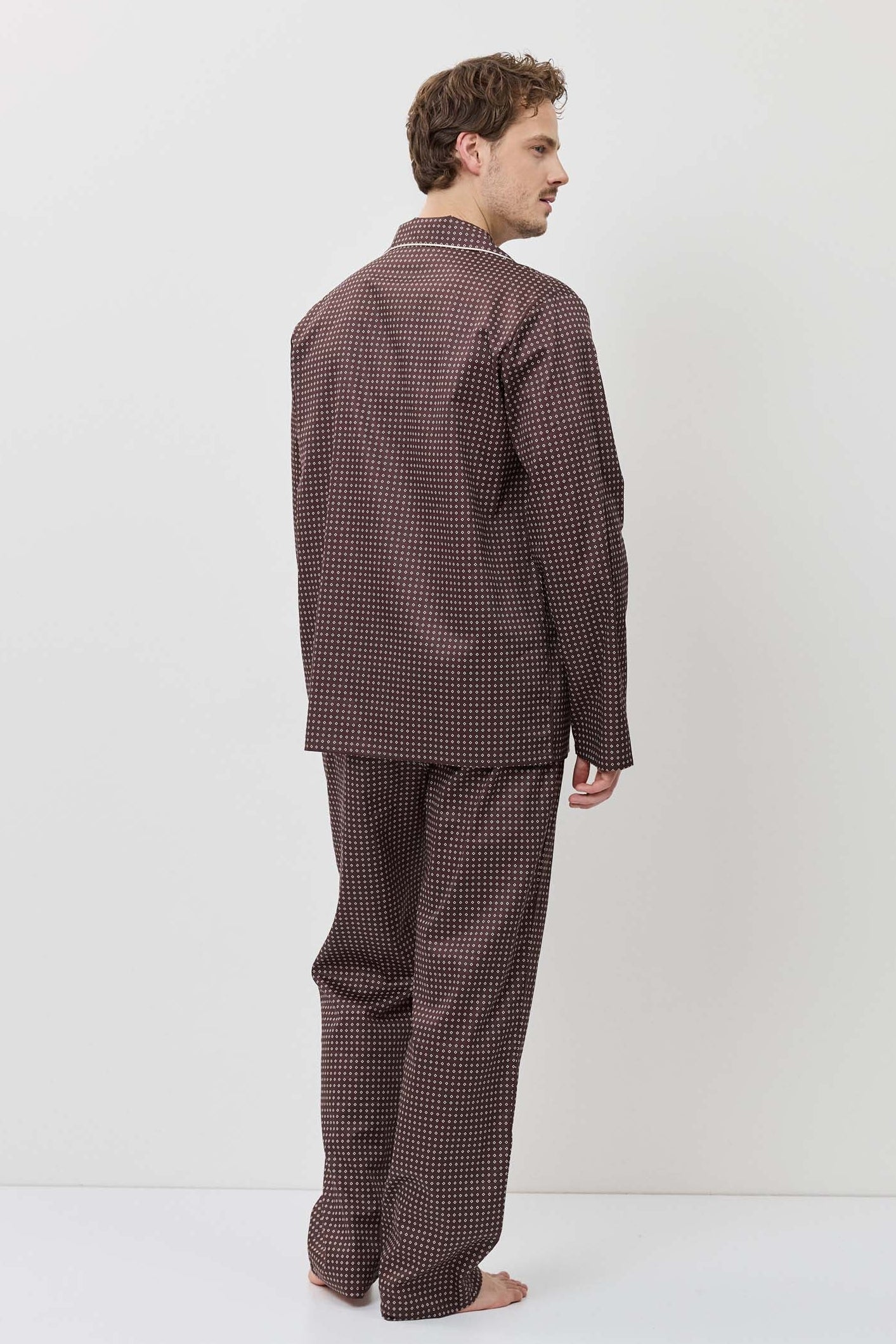 Man wearing a brown checkered pajama set against a white background