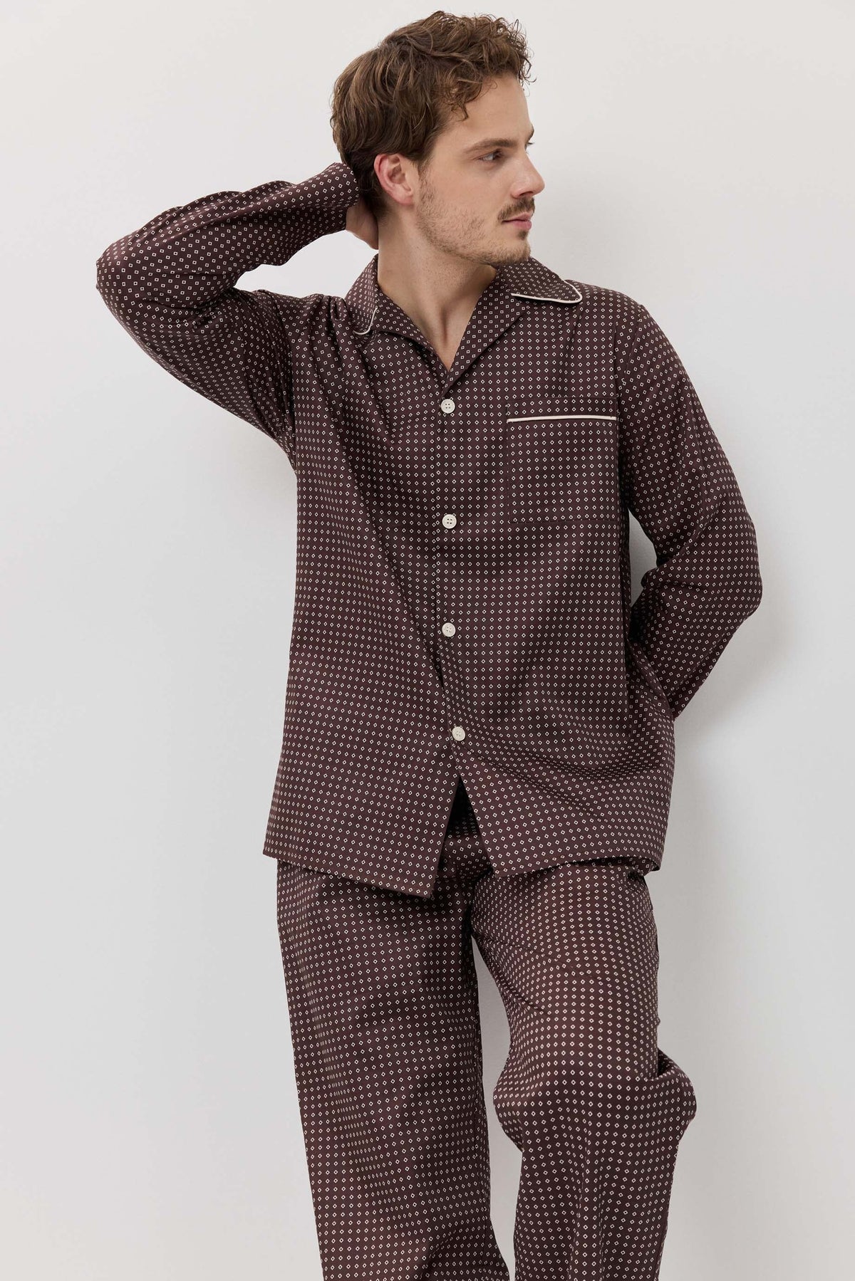Man wearing a brown checkered pajama set against a white background