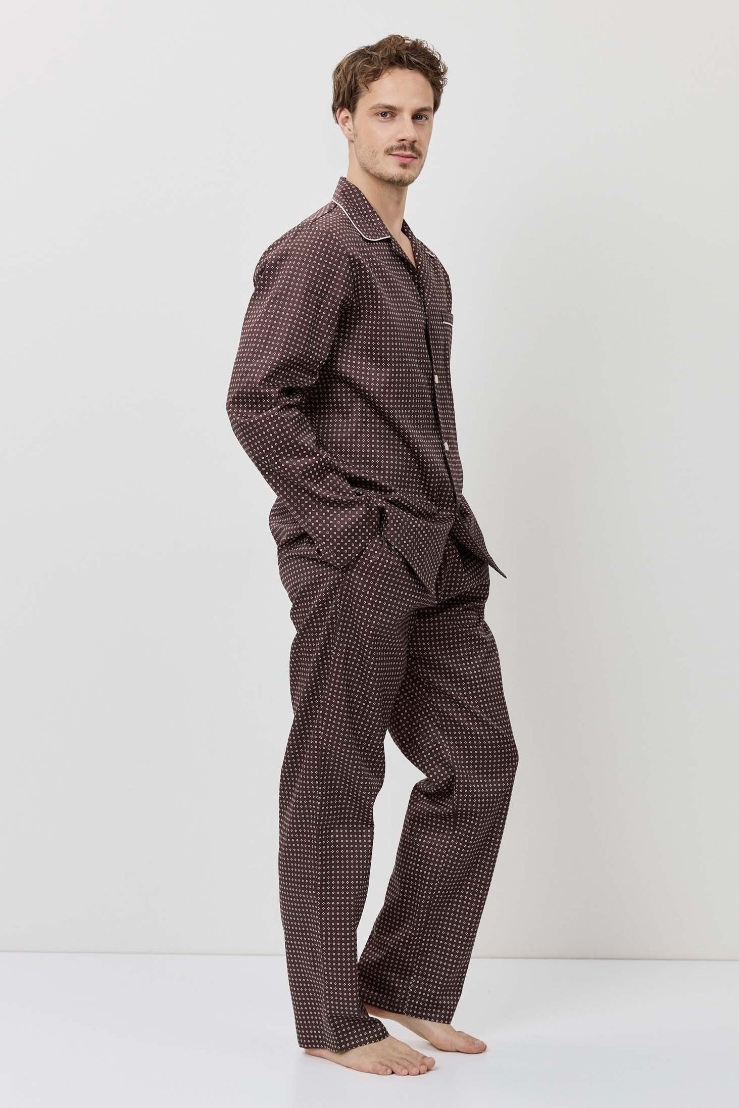 Man wearing a brown checkered pajama set on a white background