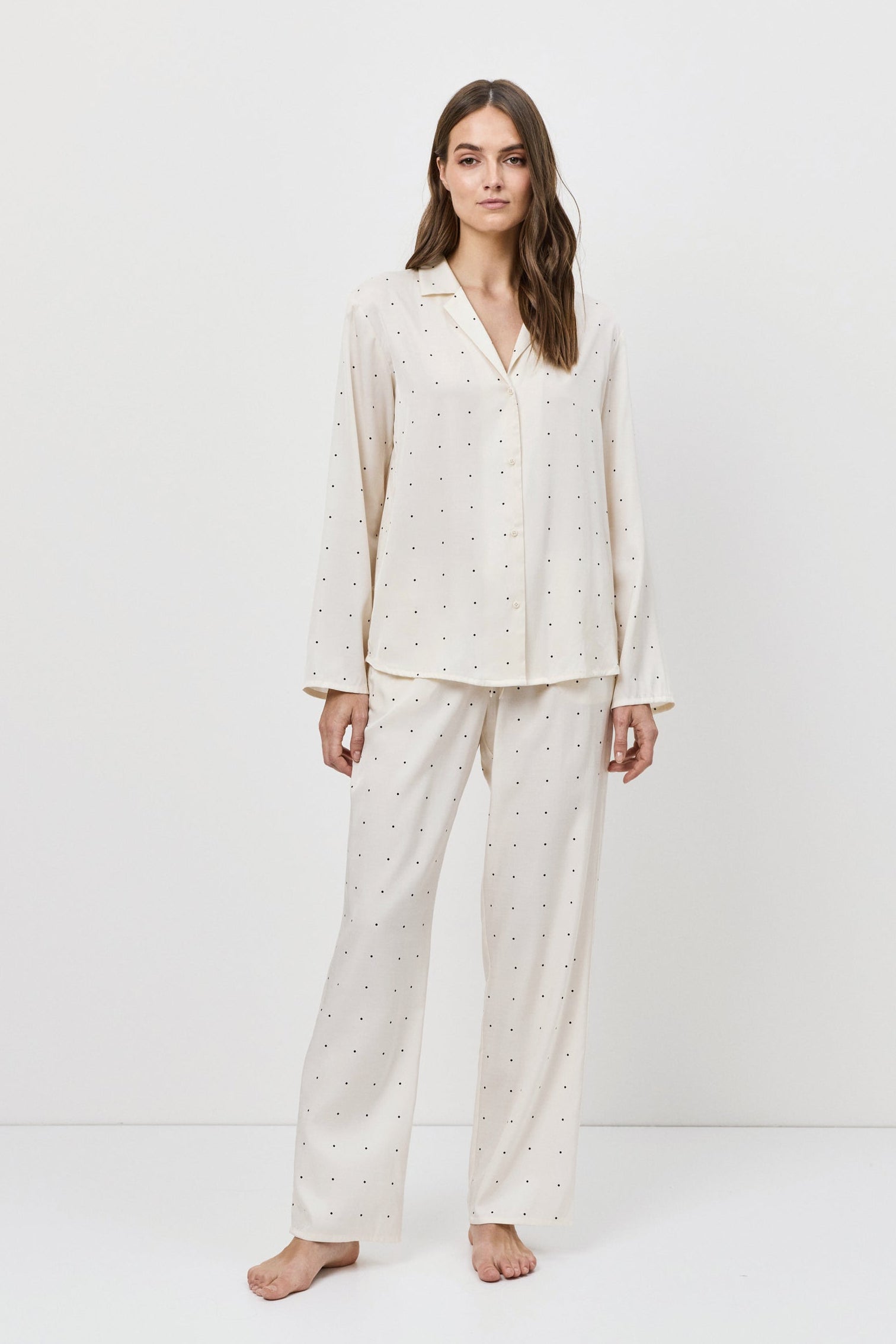 Woman wearing a white pajama set against a white background