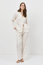 Woman wearing a white pajama set against a plain background