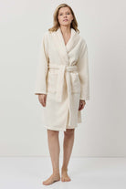 Woman wearing a cream-colored robe against a white background
