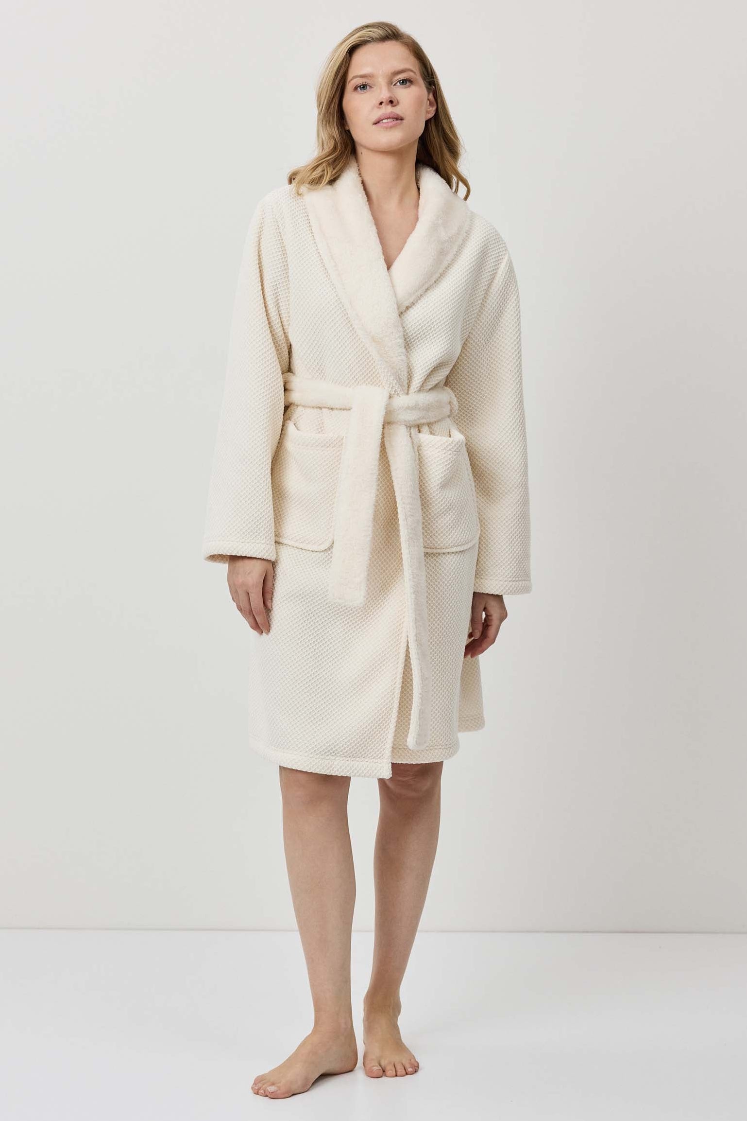Woman wearing a cream-colored robe against a white background