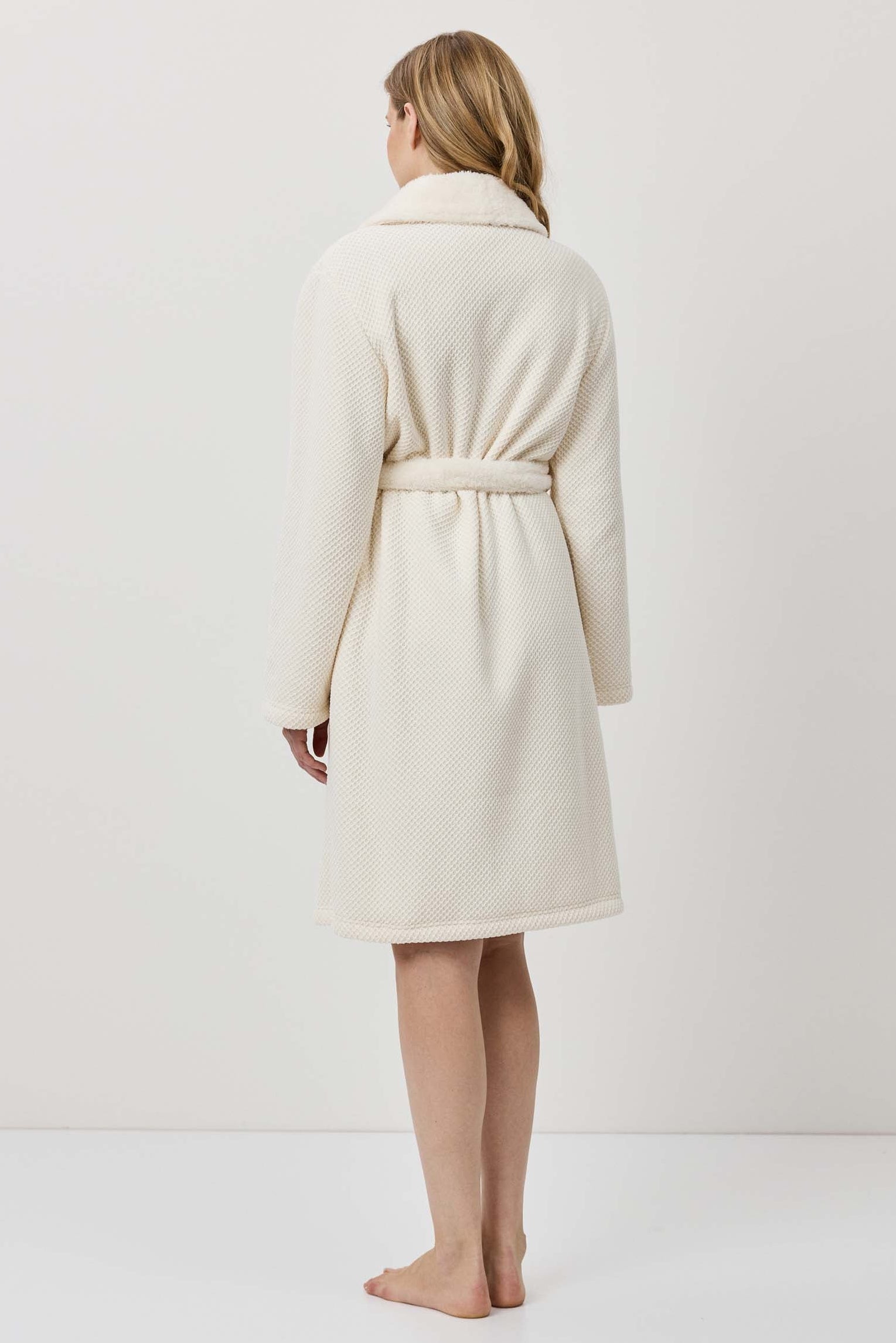 Woman wearing a cream-colored robe against a white background