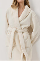 Woman wearing a cream-colored robe against a white background