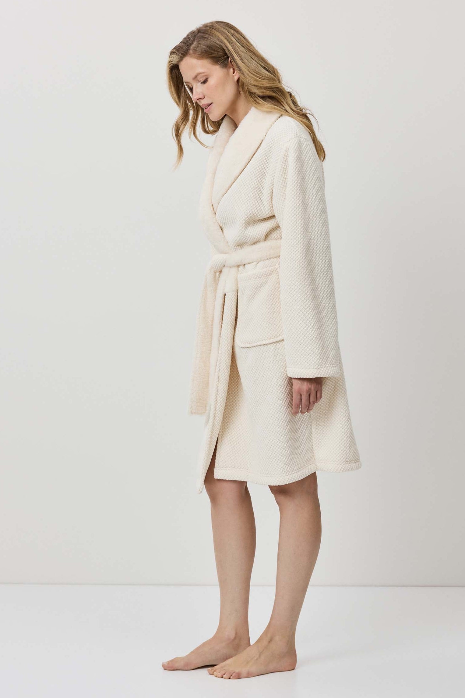 Woman wearing a cream-colored robe against a white background