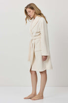 Woman wearing a cream-colored robe against a white background