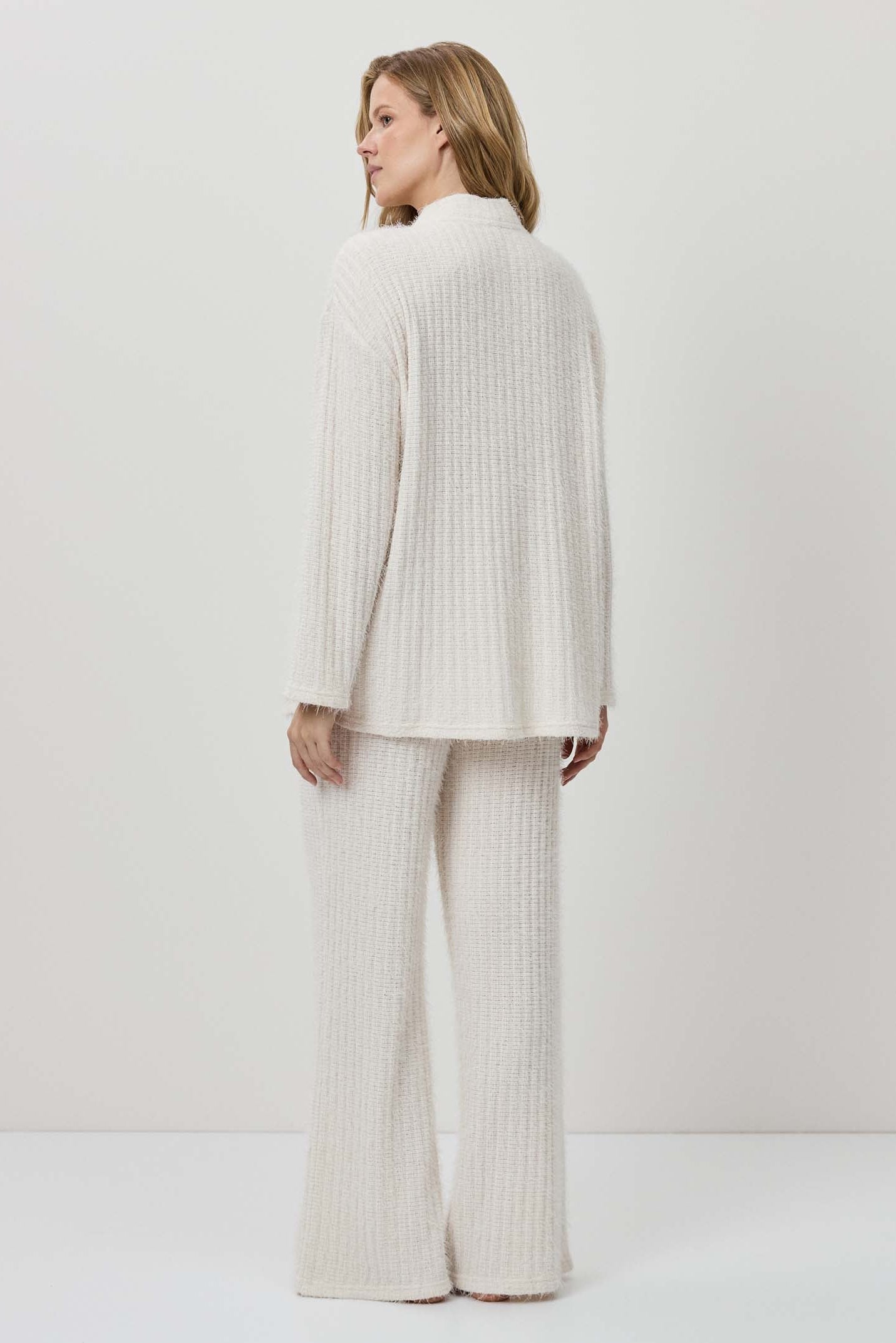 Woman wearing a white ribbed knit outfit against a plain background