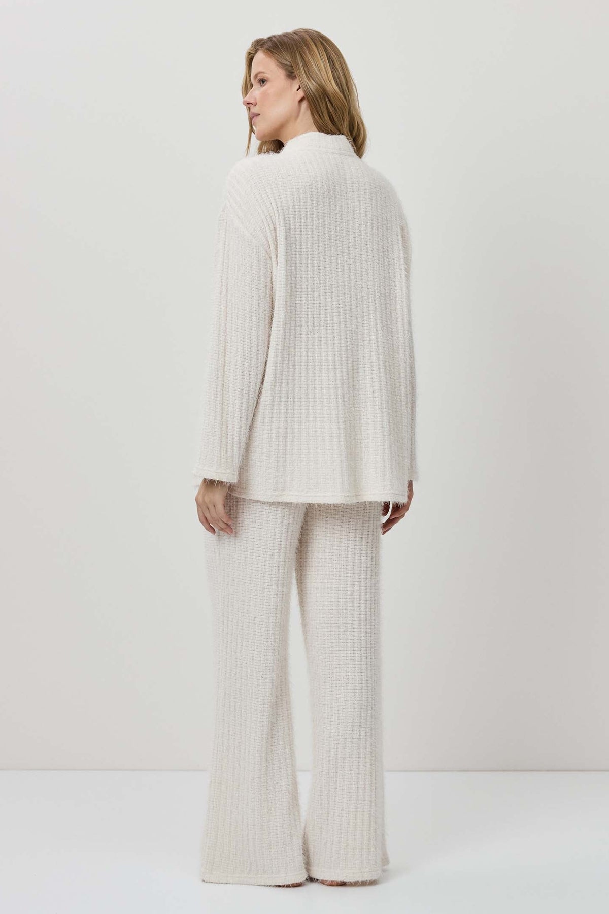 Woman wearing a white ribbed knit outfit against a plain background