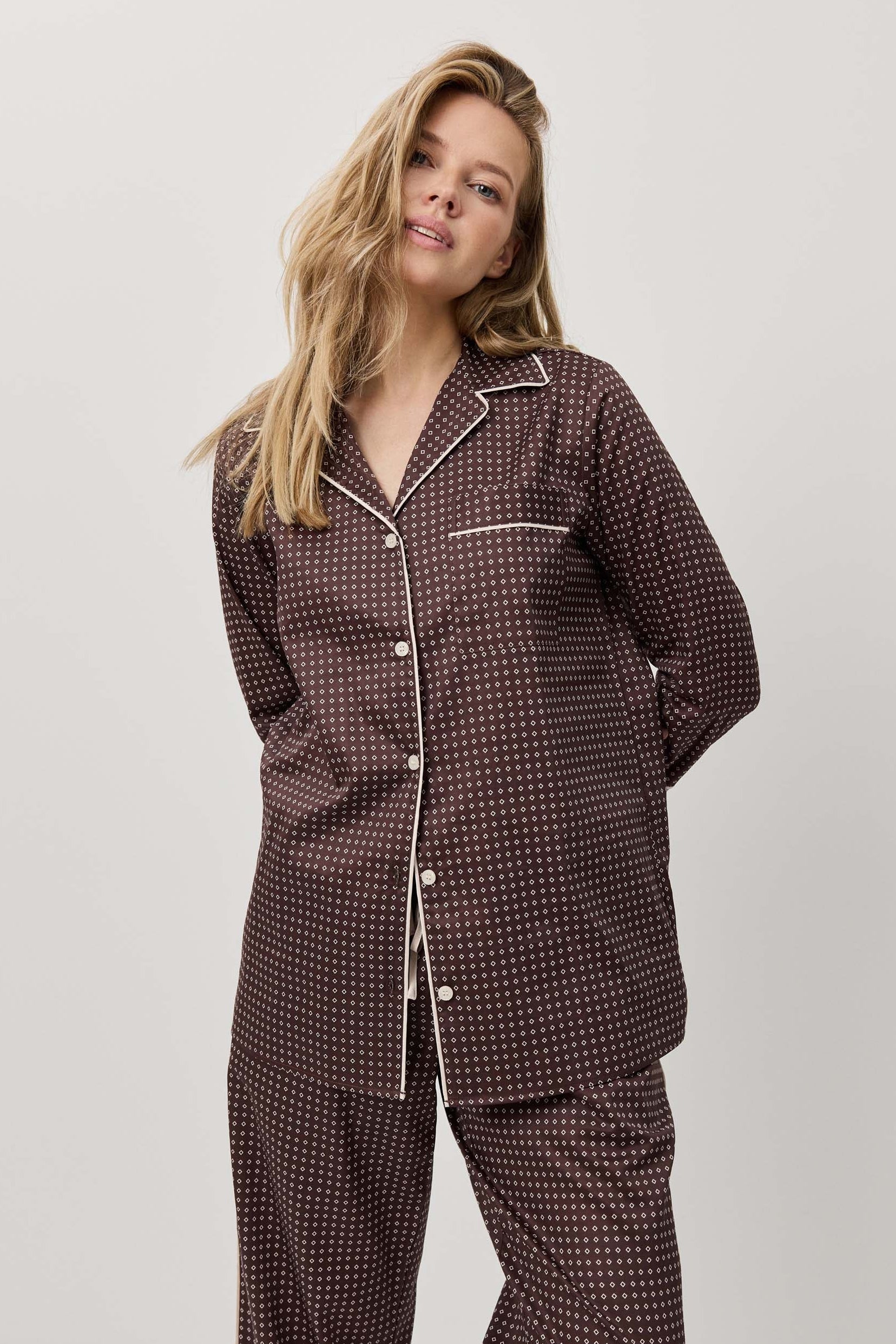 Woman wearing a dark patterned pajama set against a white background
