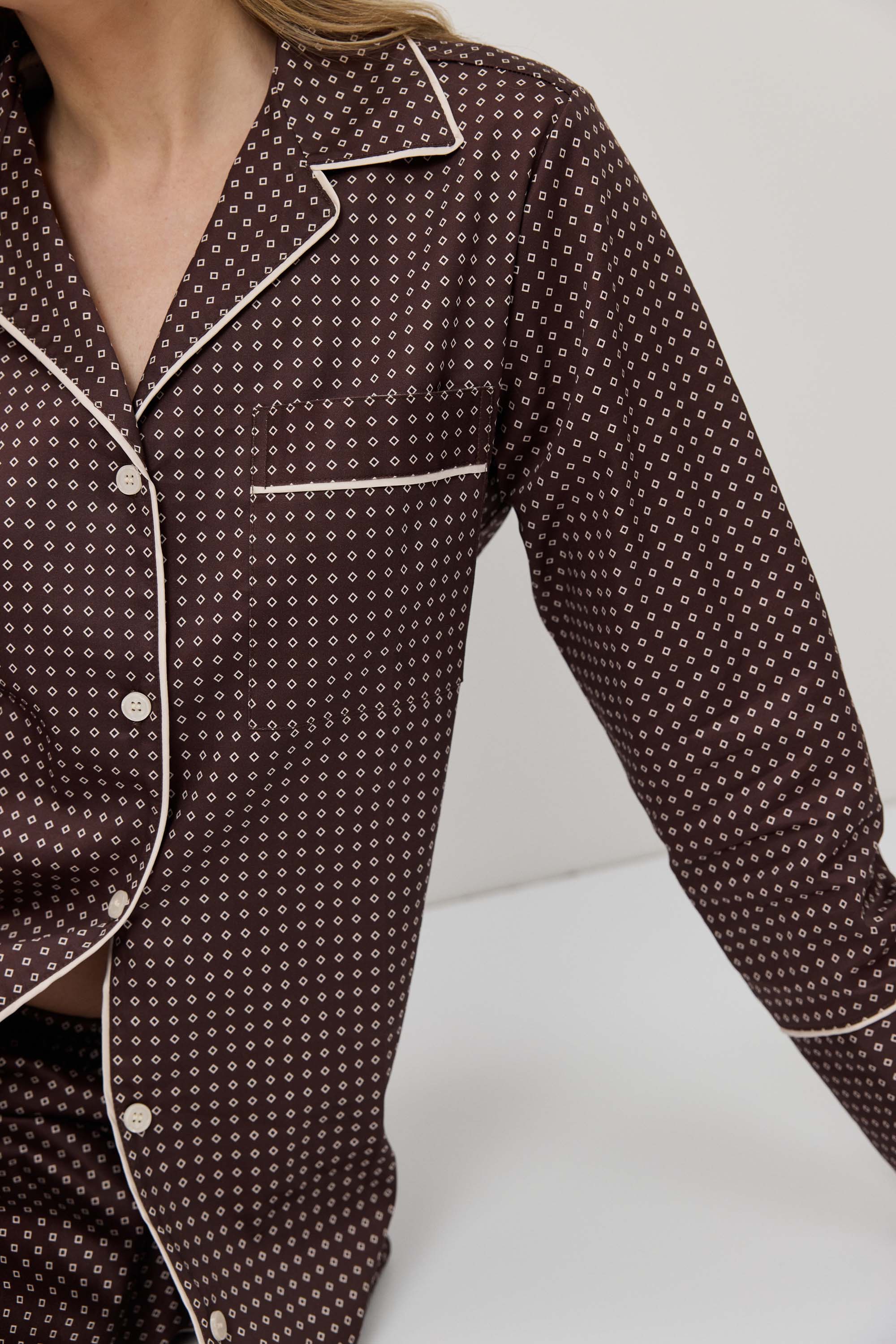 Brown patterned pajama top with white trim on a neutral background