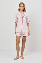 Woman wearing a pink pajama set against a white background