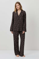 Woman wearing a black patterned pajama set on a white background