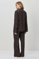 Woman wearing a black patterned pajama set on a white background