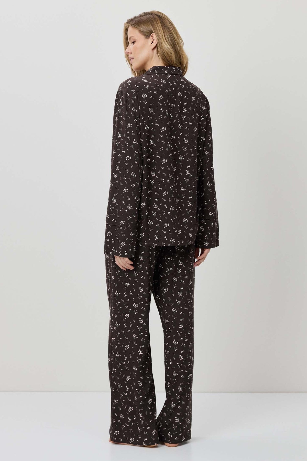 Woman wearing a black patterned pajama set on a white background