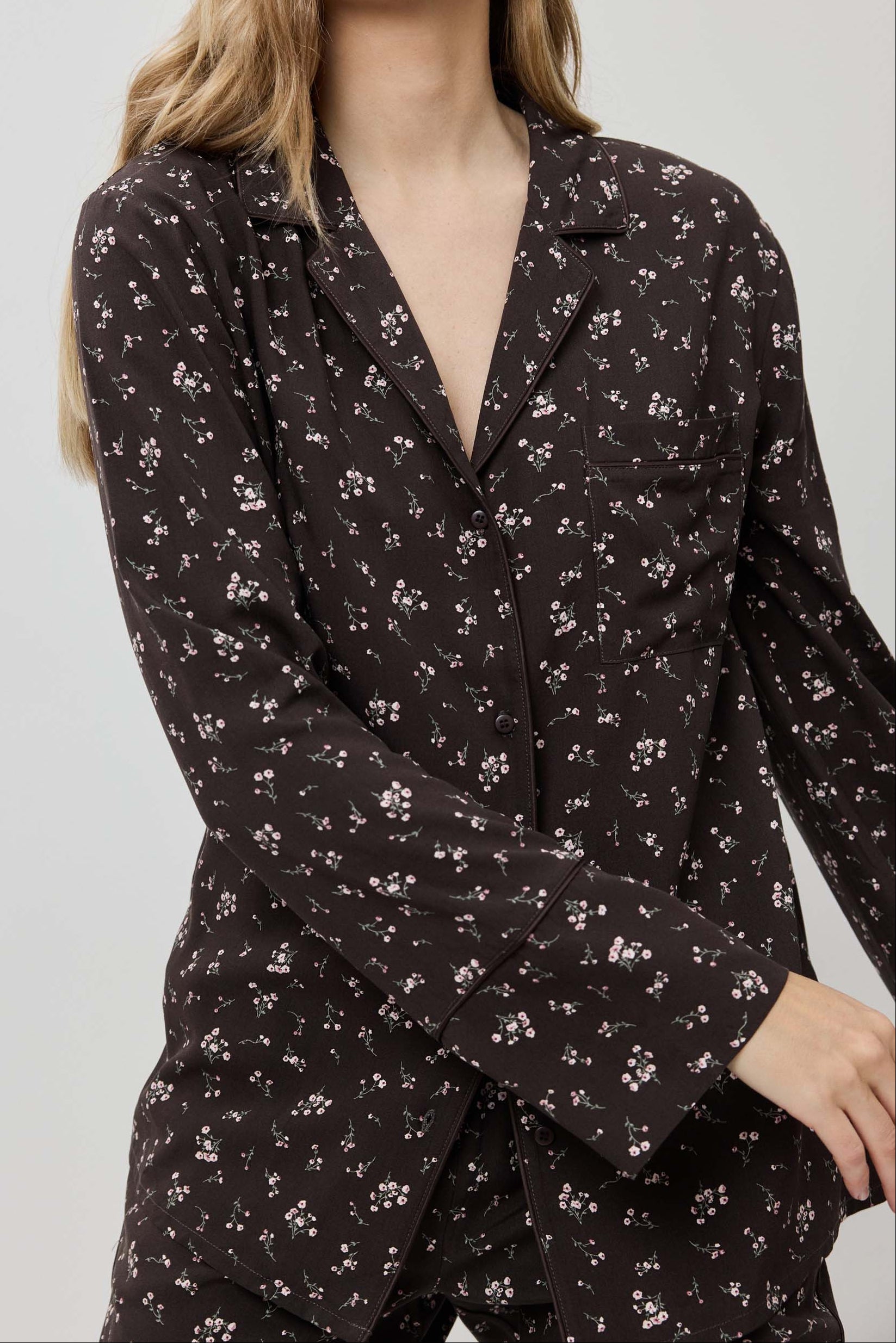 Woman wearing a dark floral patterned outfit against a plain background