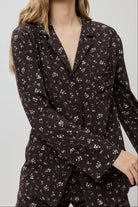 Woman wearing a dark floral patterned outfit against a plain background
