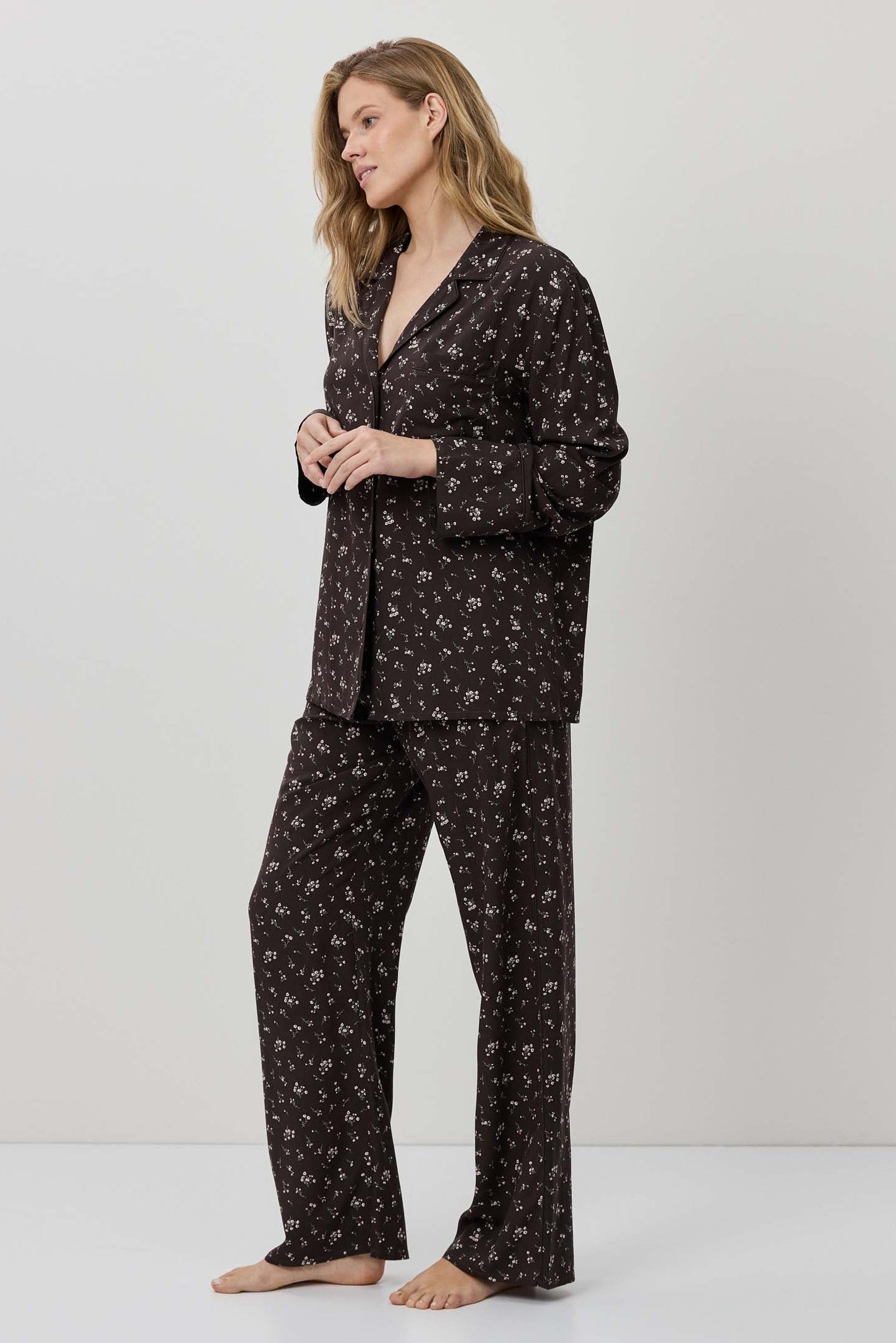 Woman wearing a dark floral pajama set on a white background