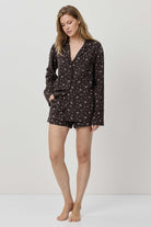Woman wearing a dark floral pajama set on a white background