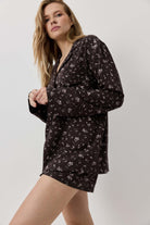 Woman wearing a black floral pajama set on a white background