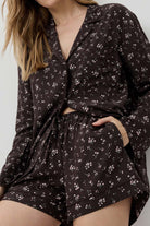 Woman wearing a dark floral pajama set against a light background