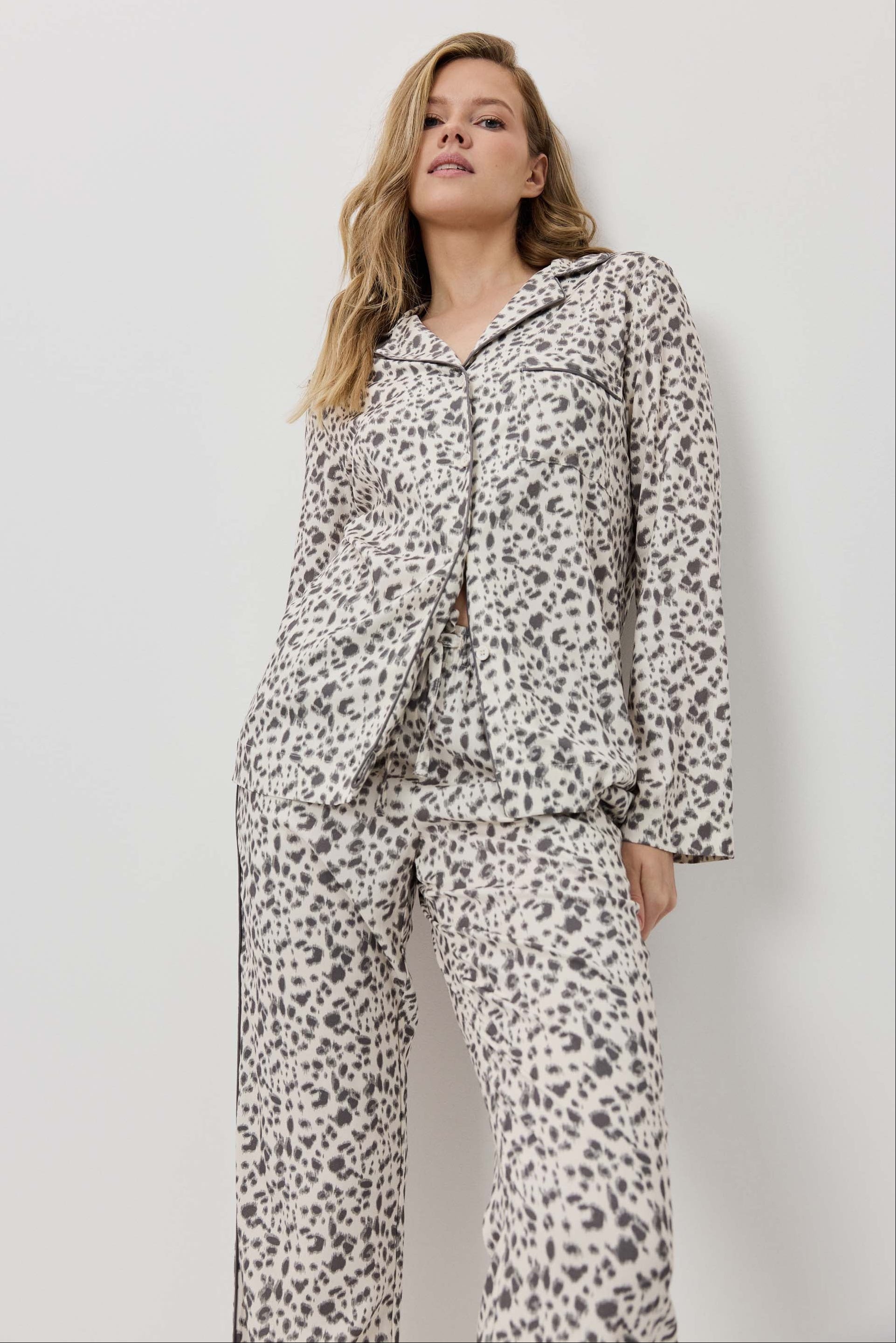Woman wearing a leopard print pajama set against a plain background