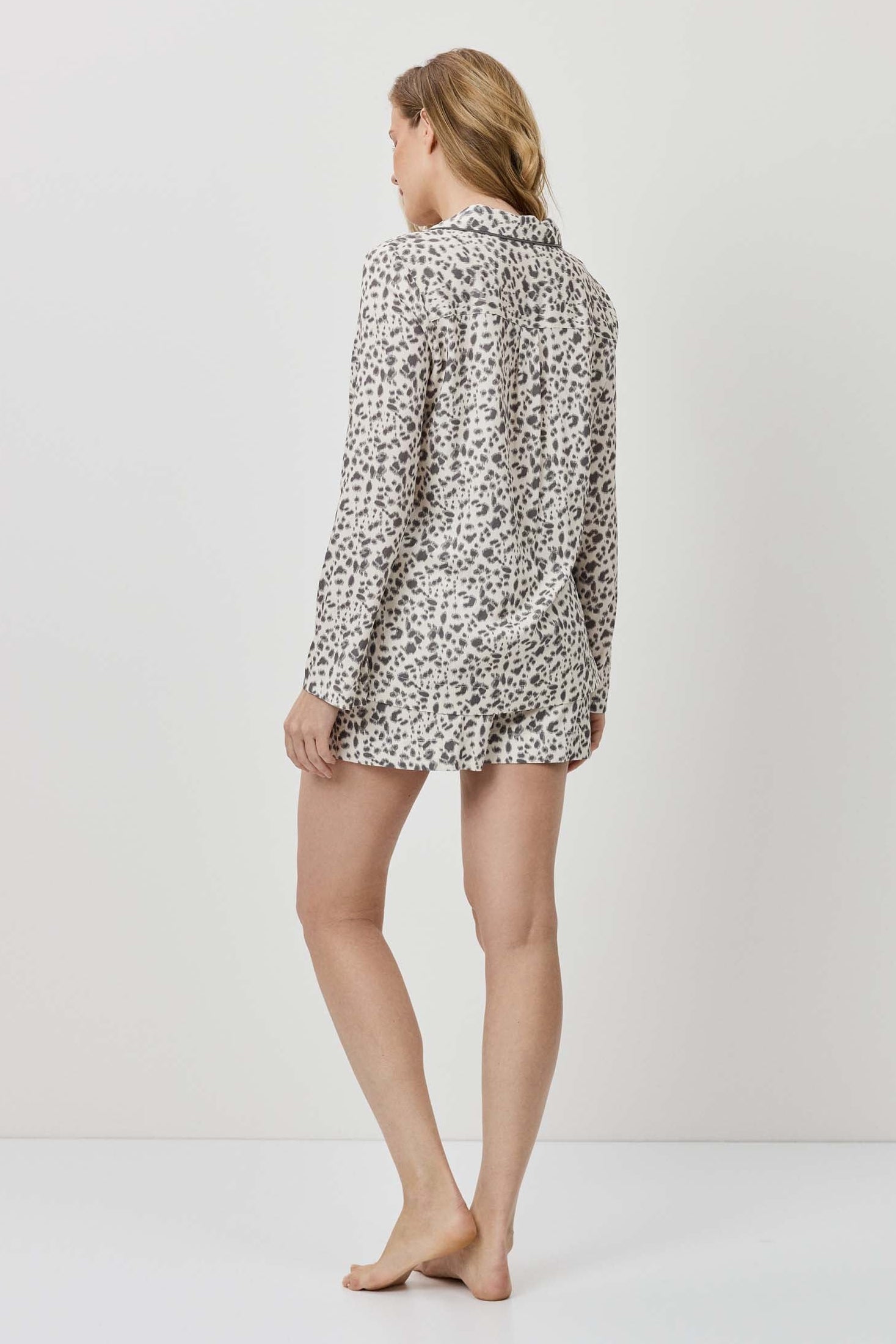 Person wearing a patterned shirt and shorts on a white background