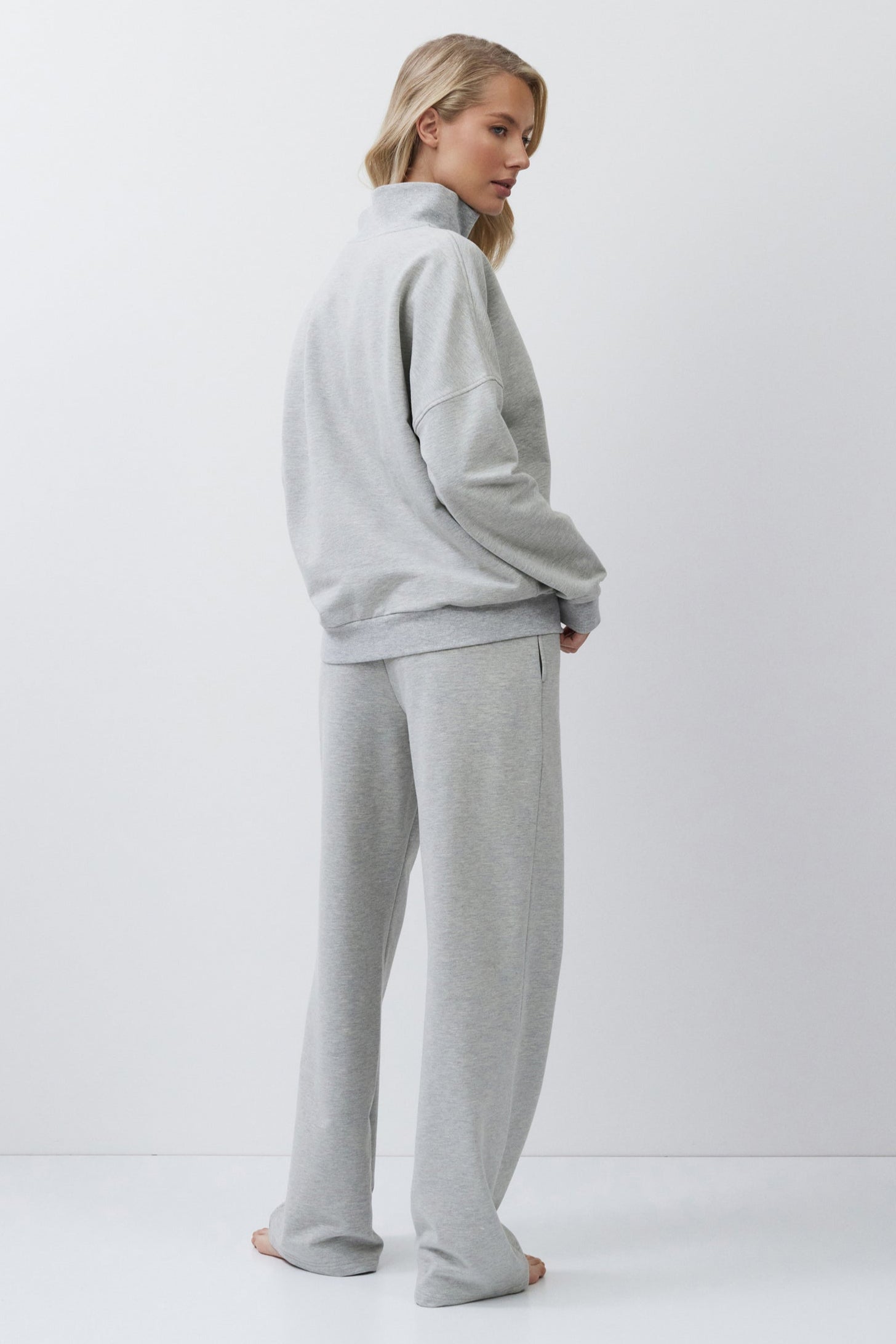 Woman wearing a gray tracksuit on a white background