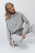 Woman wearing a gray sweatshirt and pants on a white background