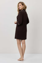Woman wearing a dark brown dress against a white background