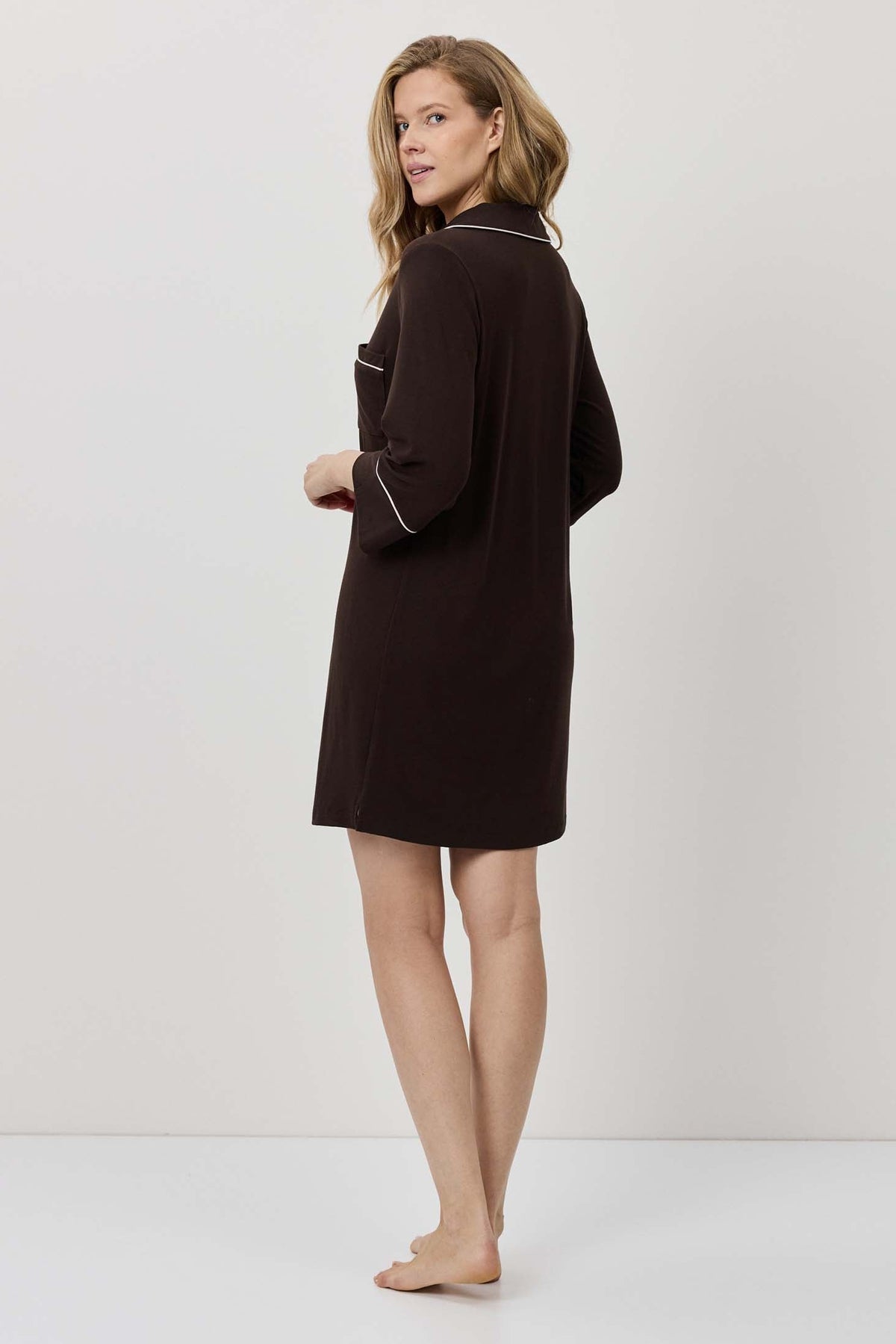 Woman wearing a dark brown dress against a white background