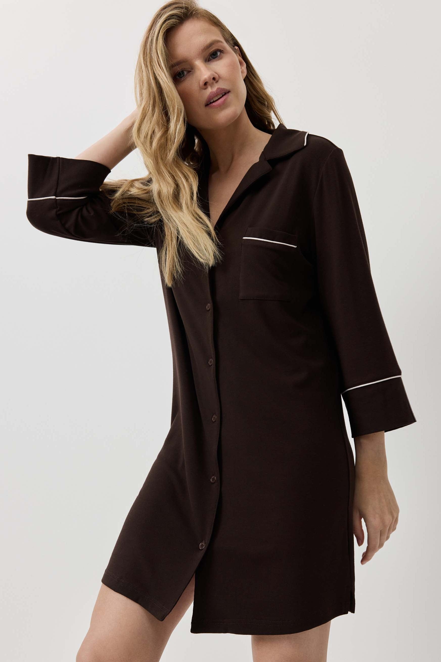 Woman wearing a brown shirt dress against a white background