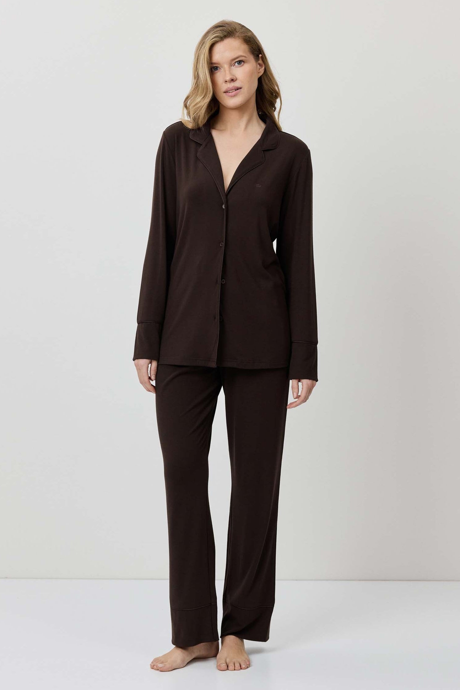 Woman wearing a brown pajama set against a white background