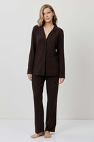 Woman wearing a brown pajama set against a white background