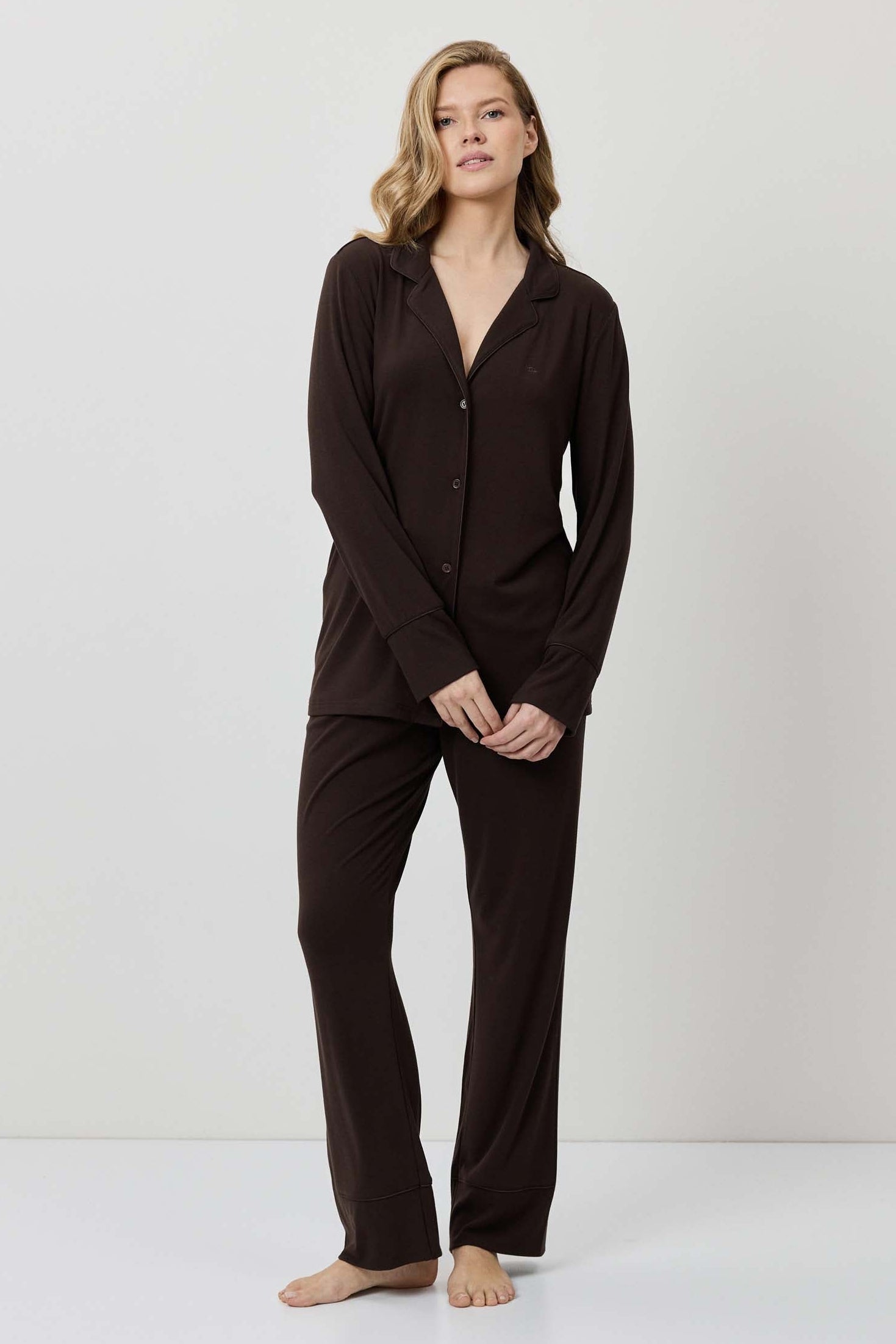 Woman wearing a dark brown pajama set against a plain background