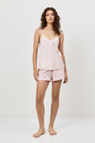 Woman wearing a light pink slip and patterned shorts on a white background