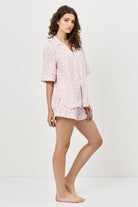 Woman wearing a pink floral pajama set on a white background