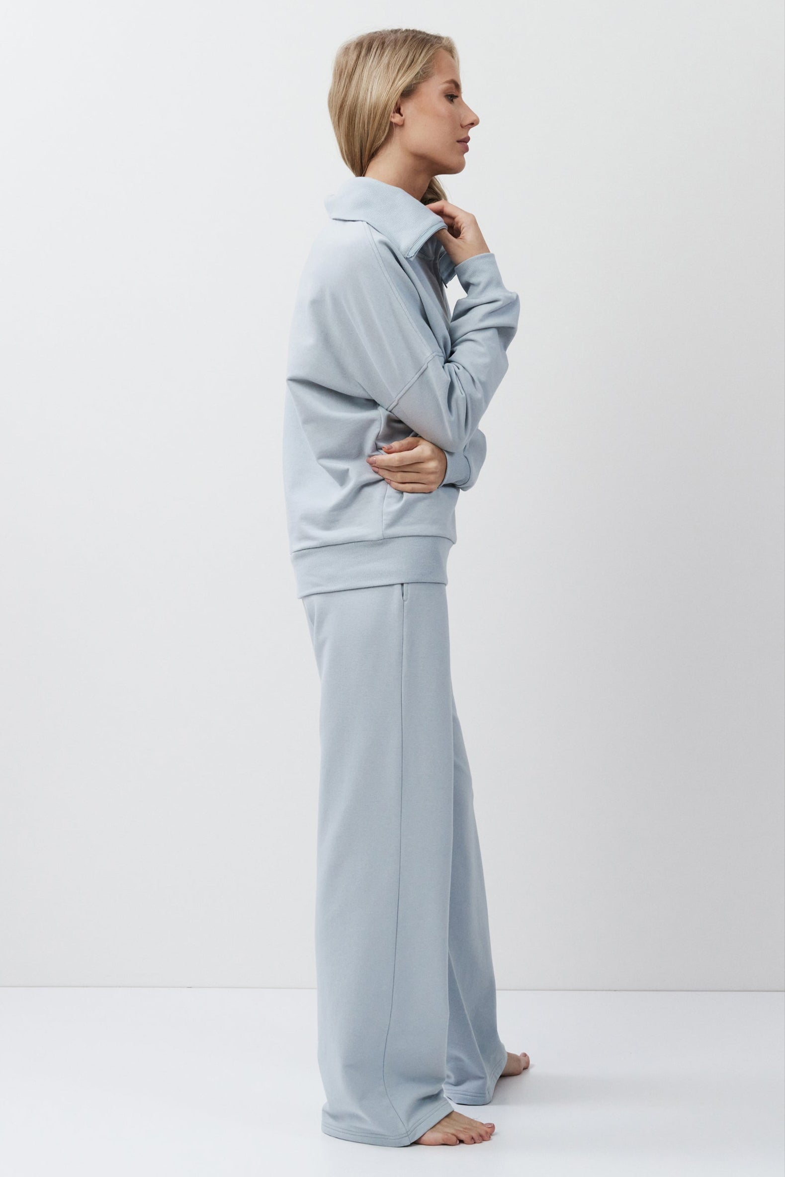 Woman wearing a light blue outfit standing against a white background