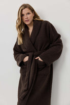 Woman wearing a brown robe against a white background