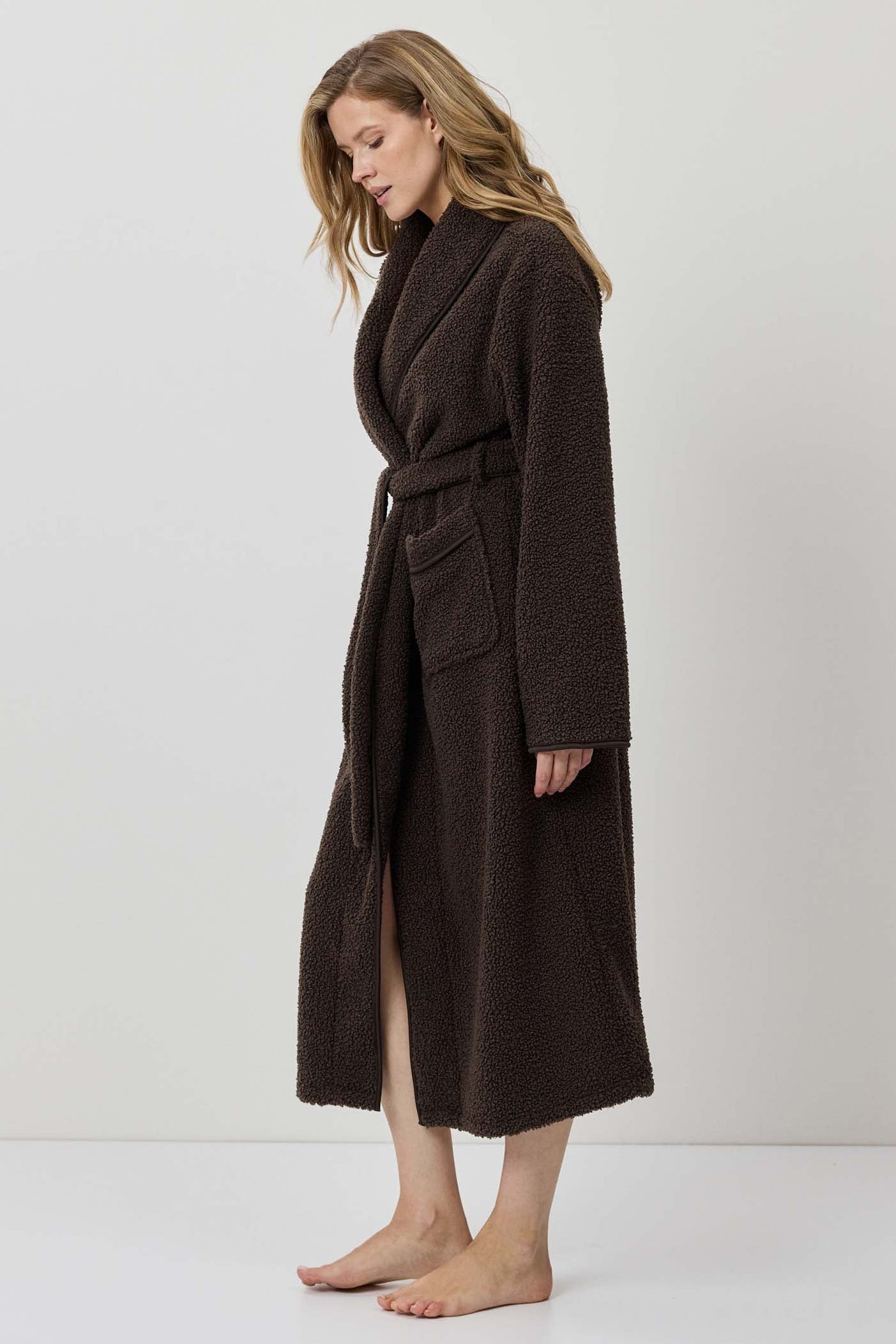 Woman wearing a brown coat against a white background