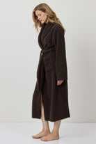Woman wearing a brown coat against a white background