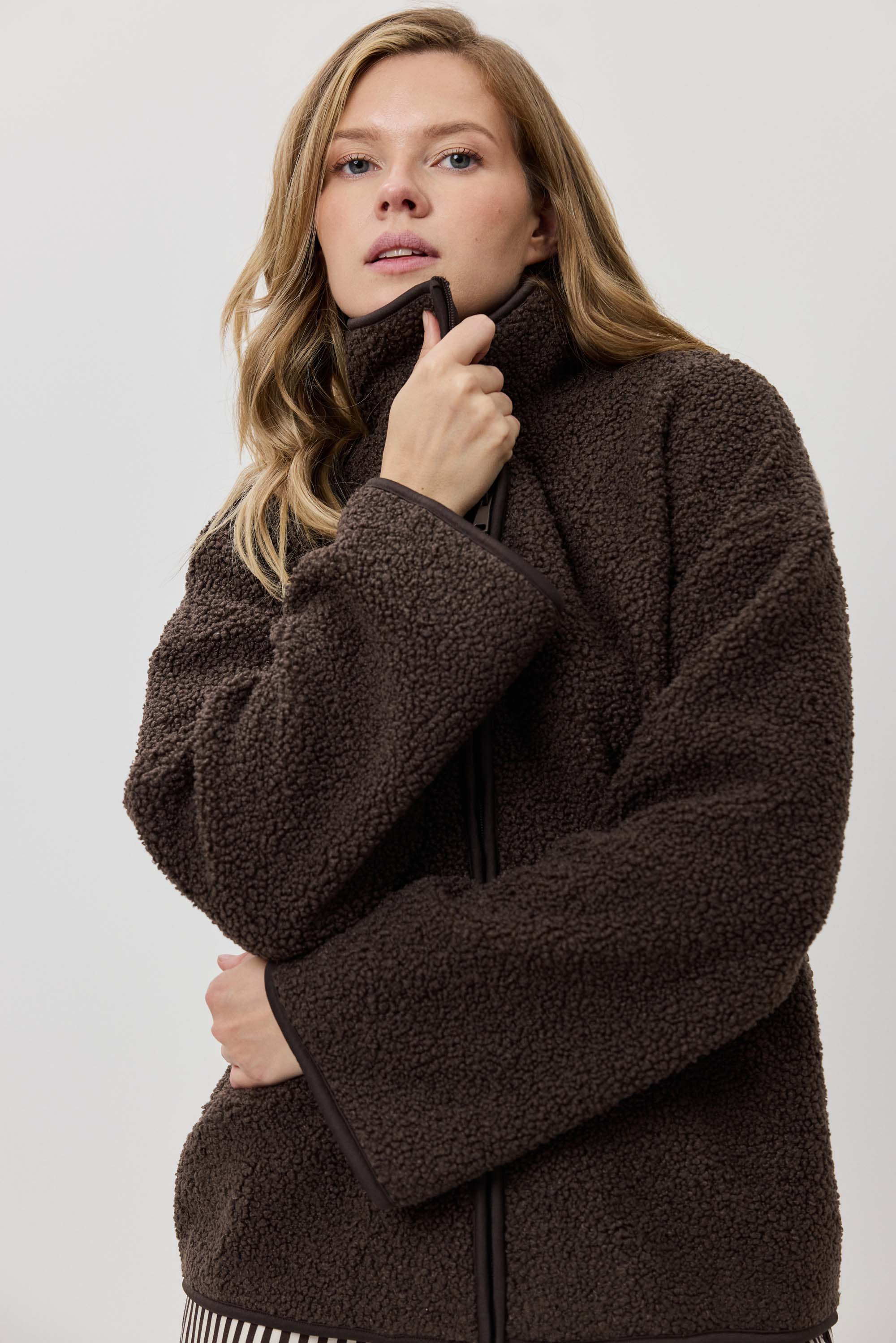Woman wearing a brown fleece jacket against a plain background