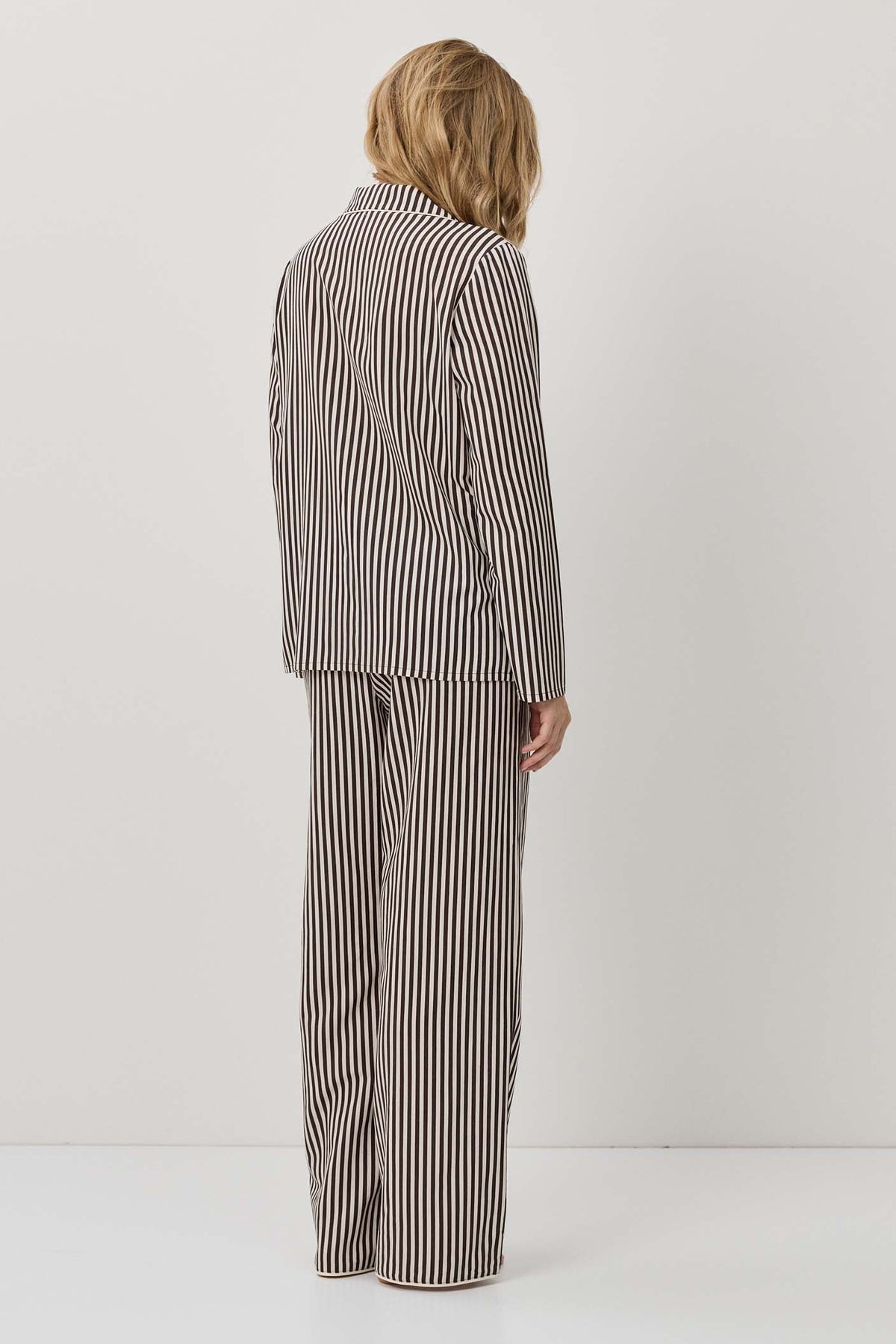 Person wearing a striped suit standing against a white background