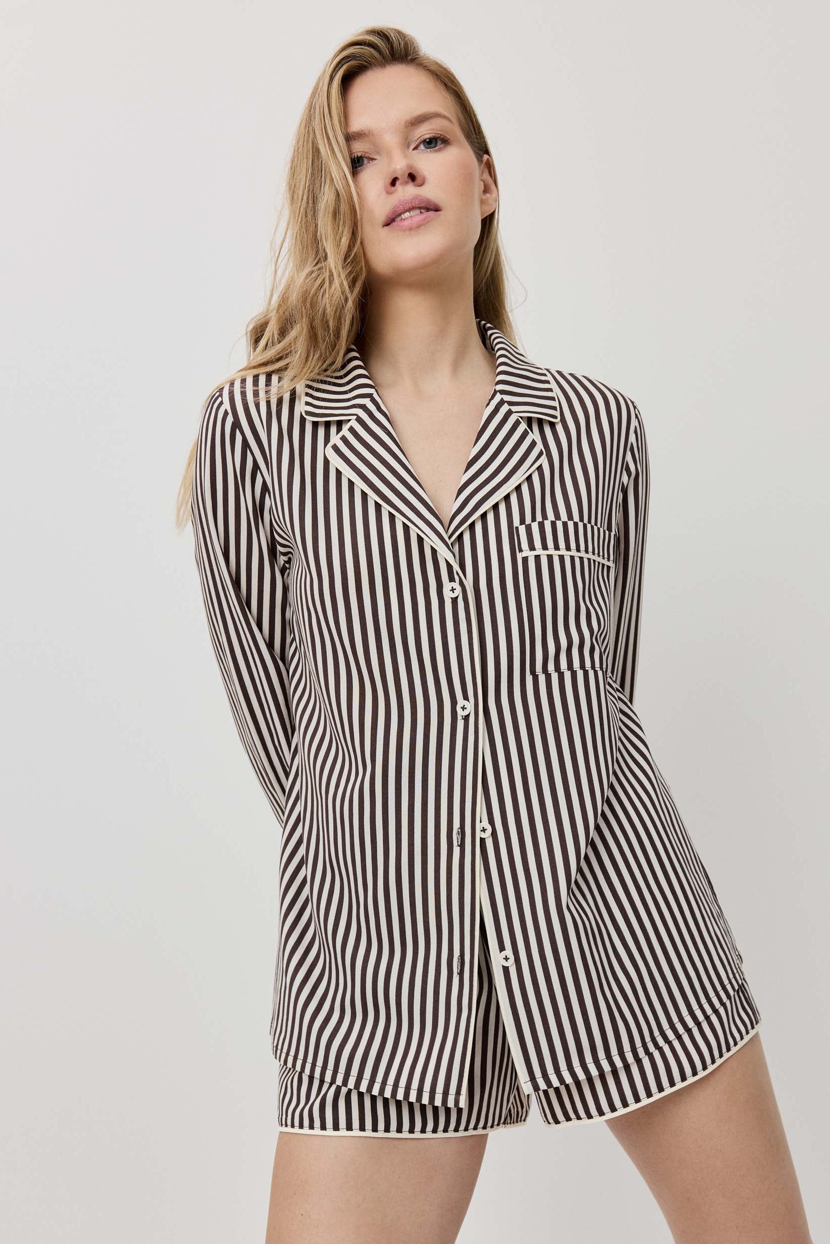 Woman wearing a black and white striped pajama set on a plain background
