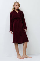 Woman wearing a burgundy robe against a white background